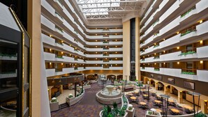 A multi-level atrium with a central fountain, multiple balconies with plants, and a variety of seating areas. - Embassy Suites by Hilton Kansas City International Airport (Kansas City)