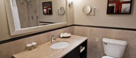 A bathroom with a double sink, a toilet, a large mirror, and a framed artwork on the wall.
