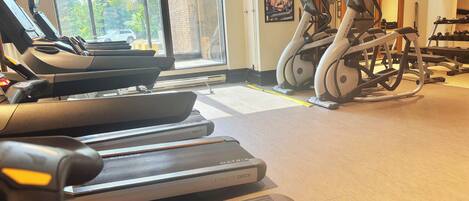 Un gimnasio con cintas de correr, elípticas y equipamiento de pesas.