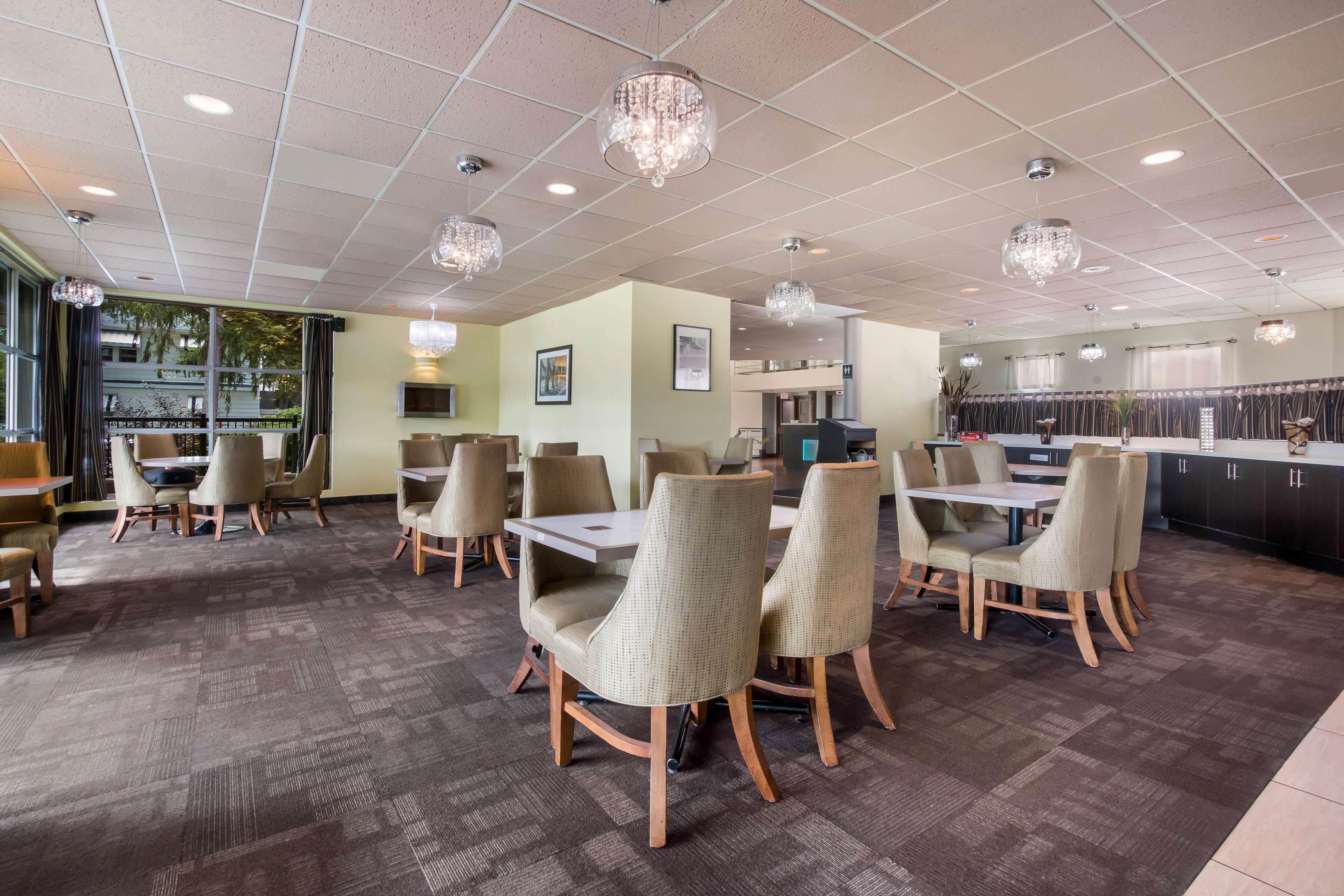 A modern dining area with a mix of round and rectangular tables, upholstered chairs, and a bar area with a counter.