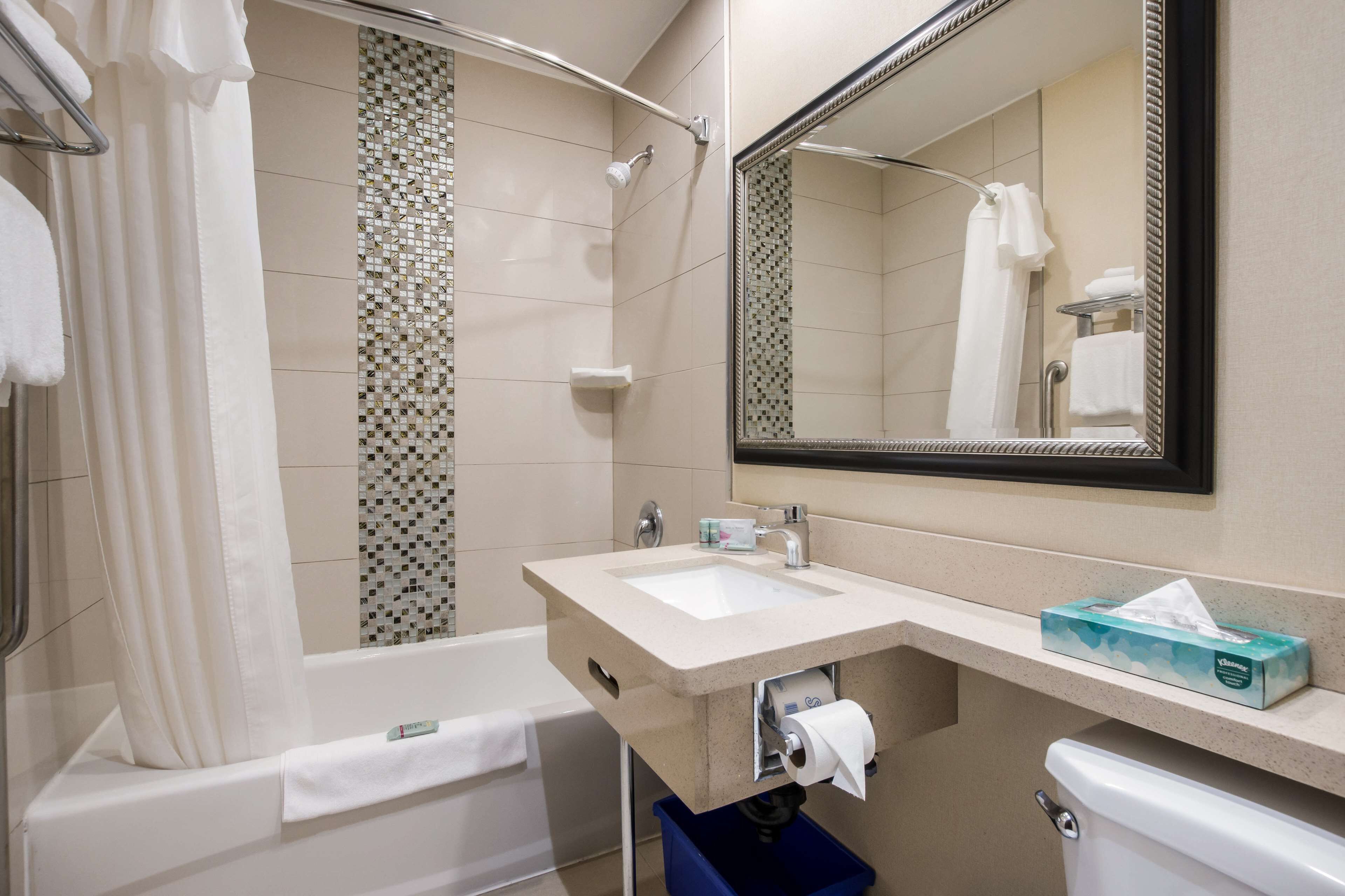 A bathroom with a bathtub, a sink, a toilet, and a mirror.