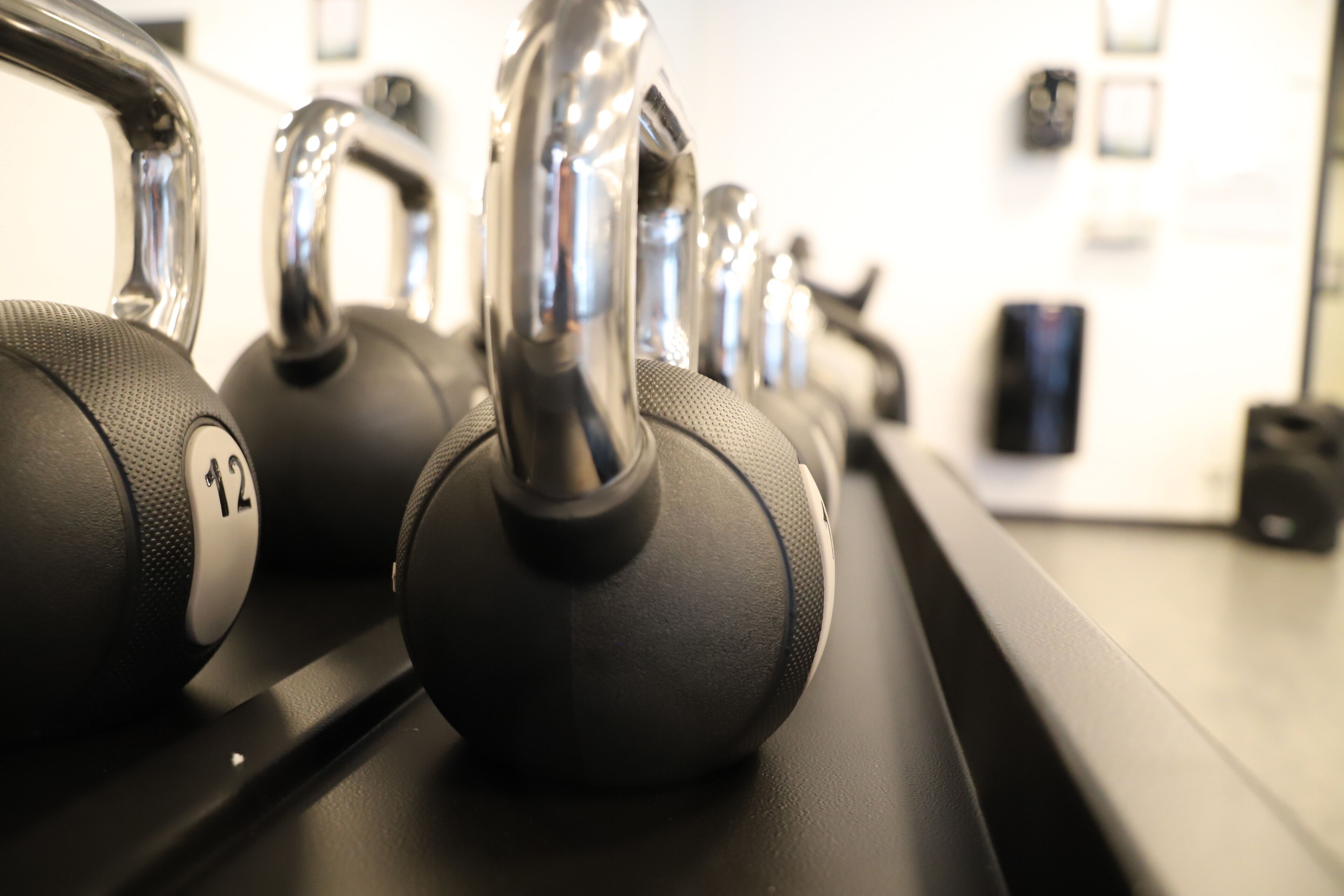A row of black dumbbells with silver handles on a black rack.
