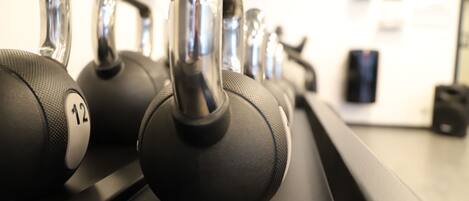 A row of black dumbbells with silver handles on a black rack.