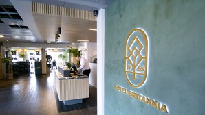 A hotel reception area with a modern design, featuring a reception desk and a large logo on the wall.