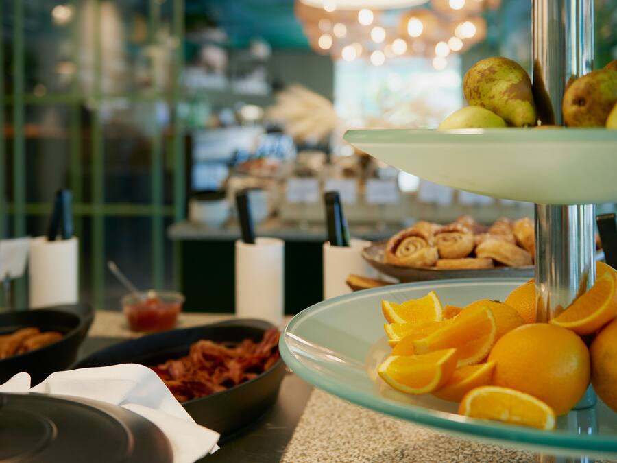 A buffet with various food items including oranges, bacon, and pastries.