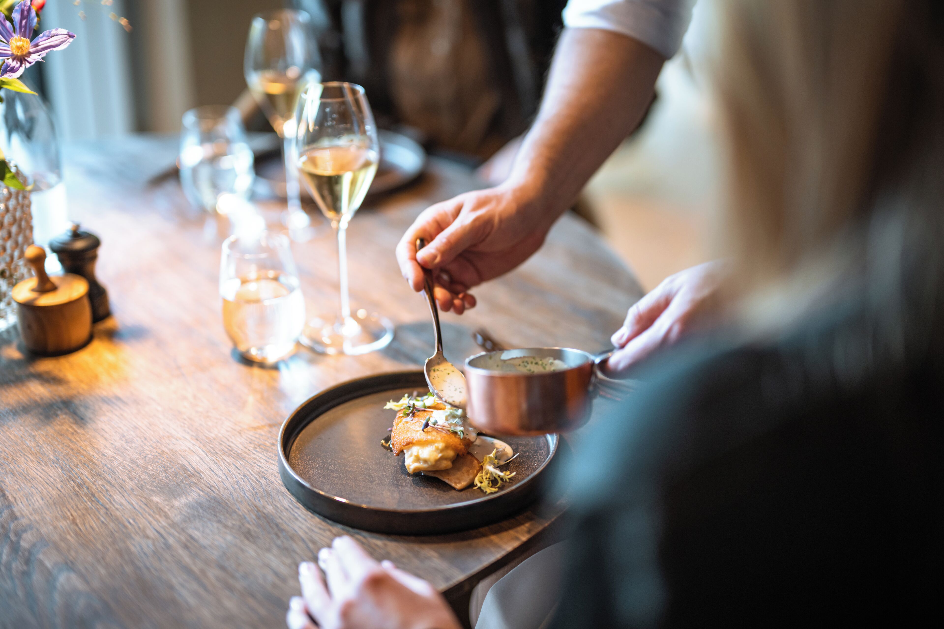 A dining table with a plate of food, a spoon, and a cup.
