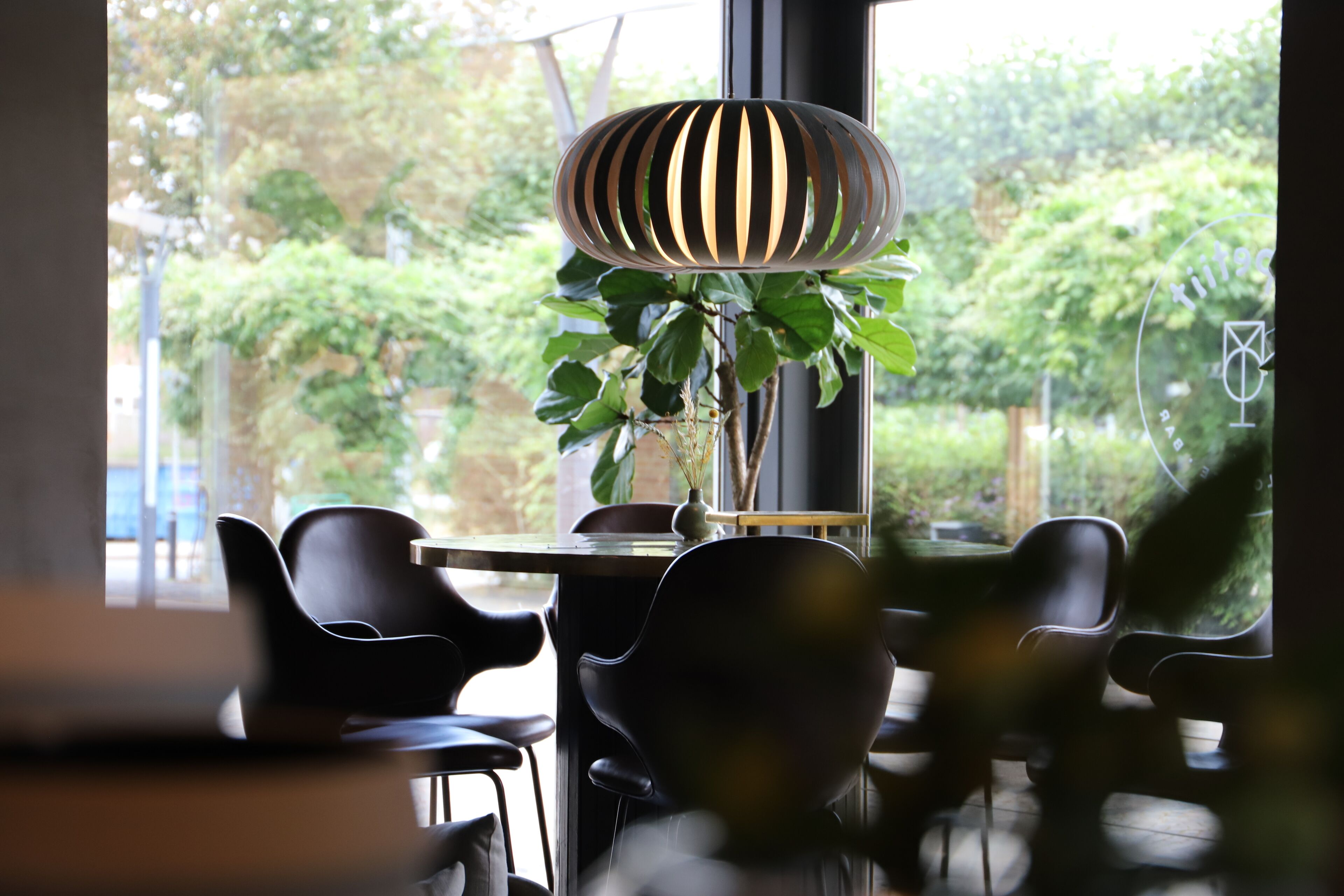 A dining area with a round table, black chairs, and a hanging light fixture.
