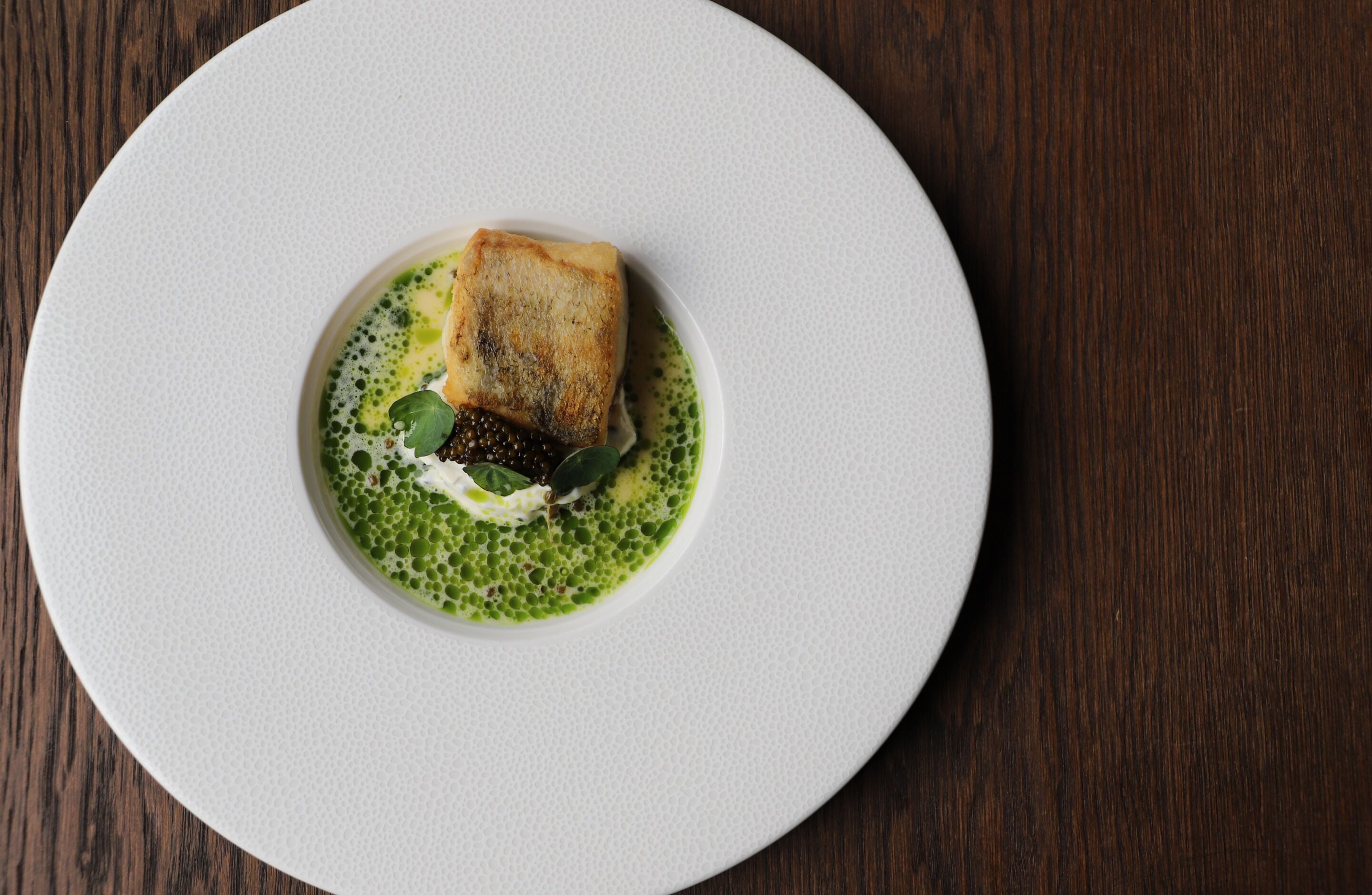 A white plate with a piece of food on a wooden table.