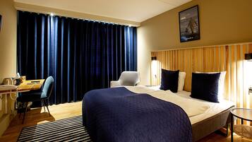 Una habitación de hotel con una cama grande, un escritorio, una silla y una mesita.