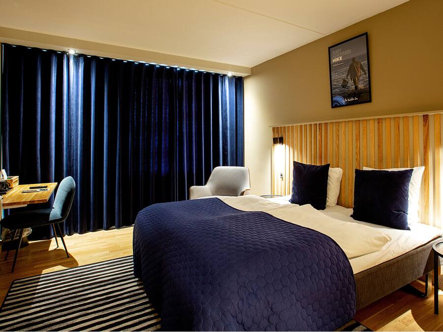 Una habitación de hotel con una cama grande, un escritorio, una silla y una mesita.
