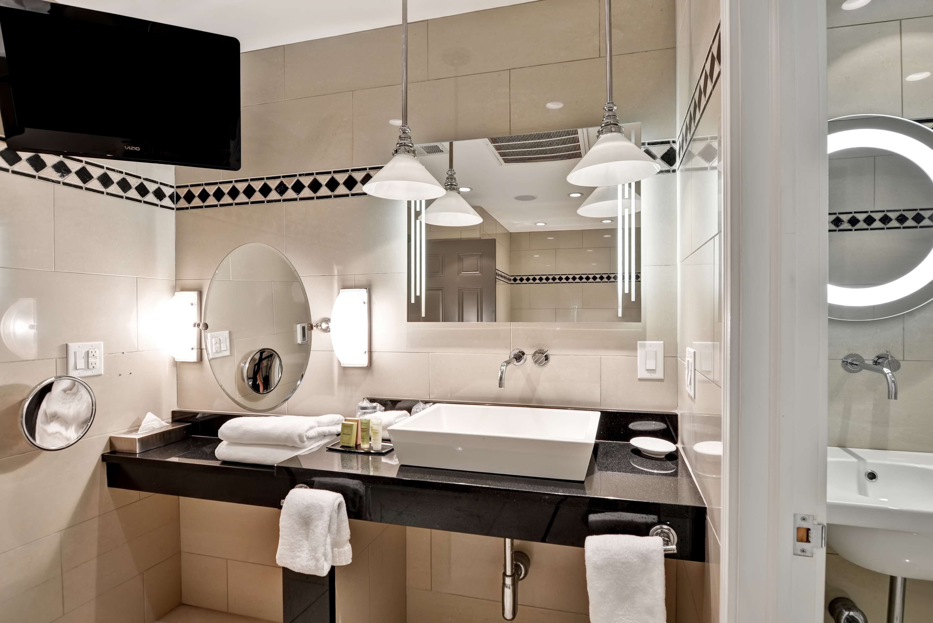 A modern bathroom with a black countertop, a large mirror, a sink, and a toilet.