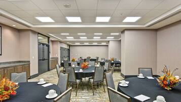 Una sala de conferencias con varias mesas, sillas y una zona de kitchenette.