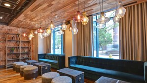 A cozy lounge area with wooden flooring, cushioned seating, and hanging pendant lights. - The Cincinnatian Hotel Curio Collection by Hilton (Cincinnati)