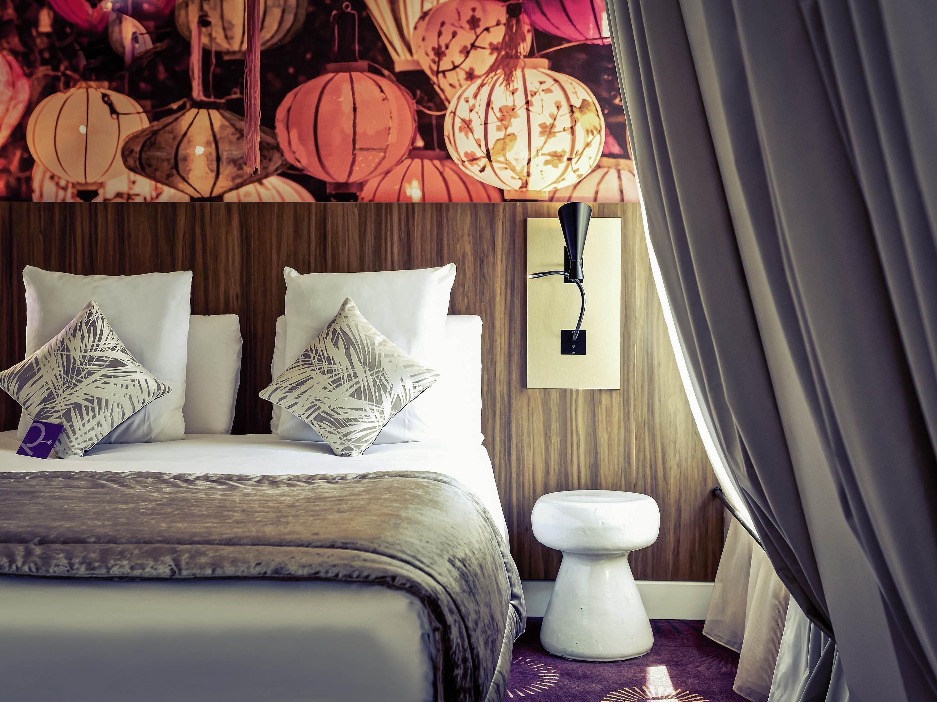A bed with two pillows, a bedside table, and a wall-mounted light fixture.