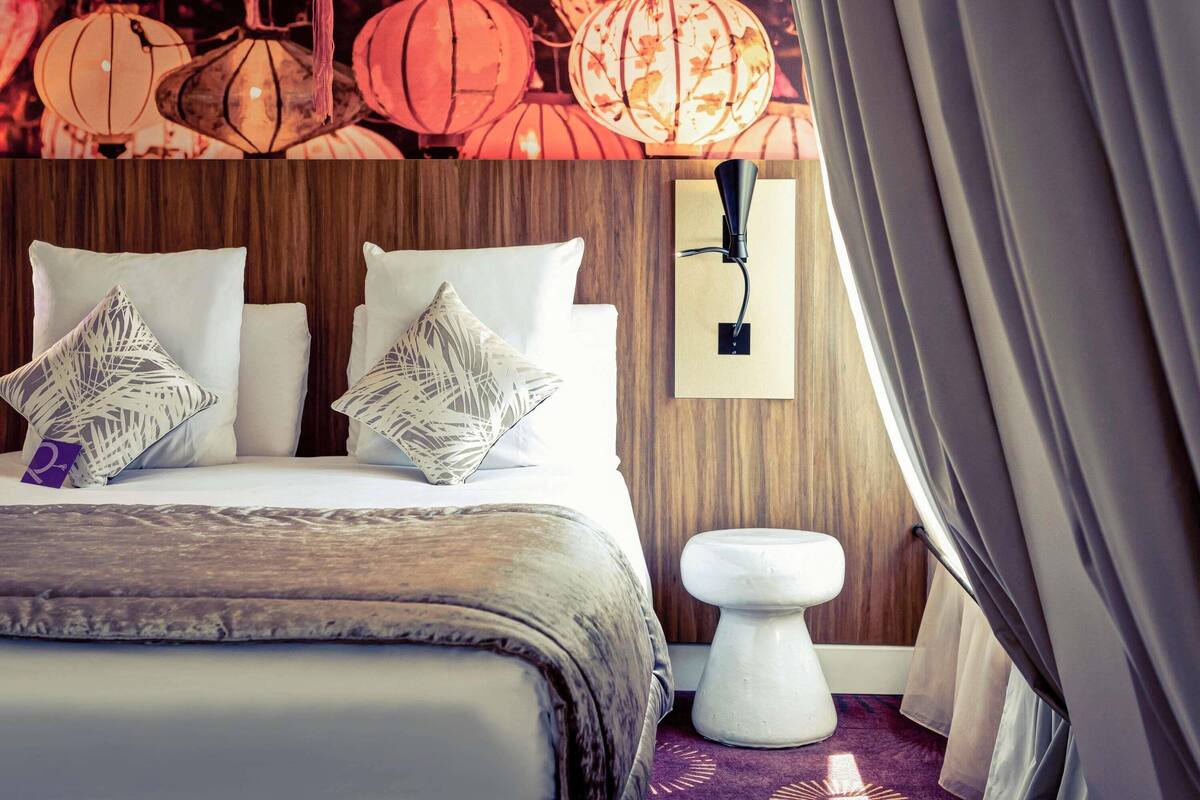 Ein Hotelzimmer mit einem hölzernen Kopfteil, weißer Bettwäsche und dekorativen Kissen.