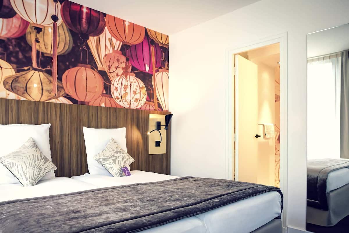 Ein Hotelzimmer mit Bett, Holz-Kopfteil, Wand mit Laternen und einer Tür zu einem weiteren Raum.