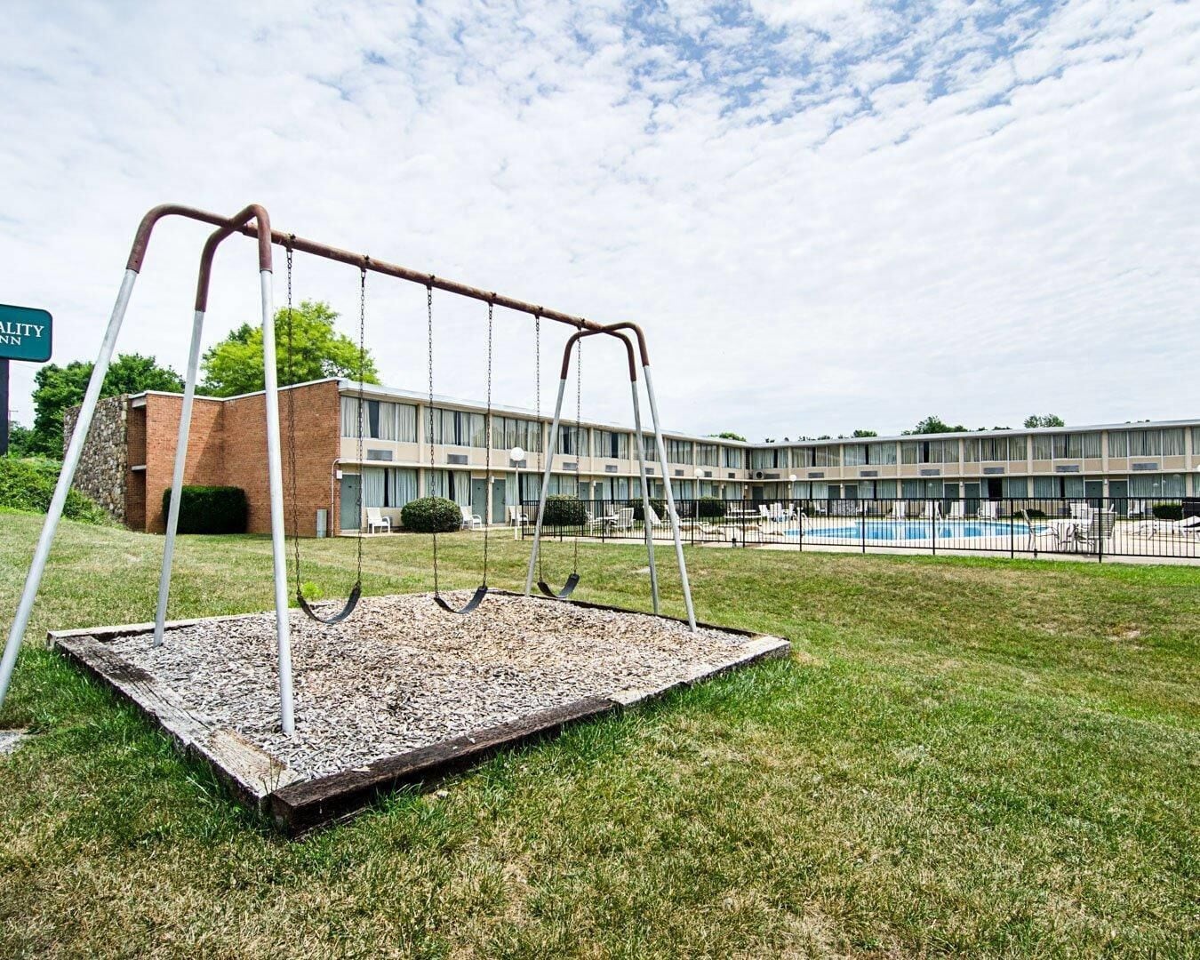 Une balançoire installée dans un espace herbeux, avec un bâtiment en arrière-plan.