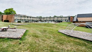 A modern building with a swimming pool, outdoor seating, and a grassy area. - Quality Inn Shenandoah Valley (New Market)