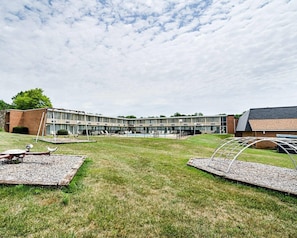 A modern building with a swimming pool, outdoor seating, and a grassy area. - Quality Inn Shenandoah Valley (New Market)