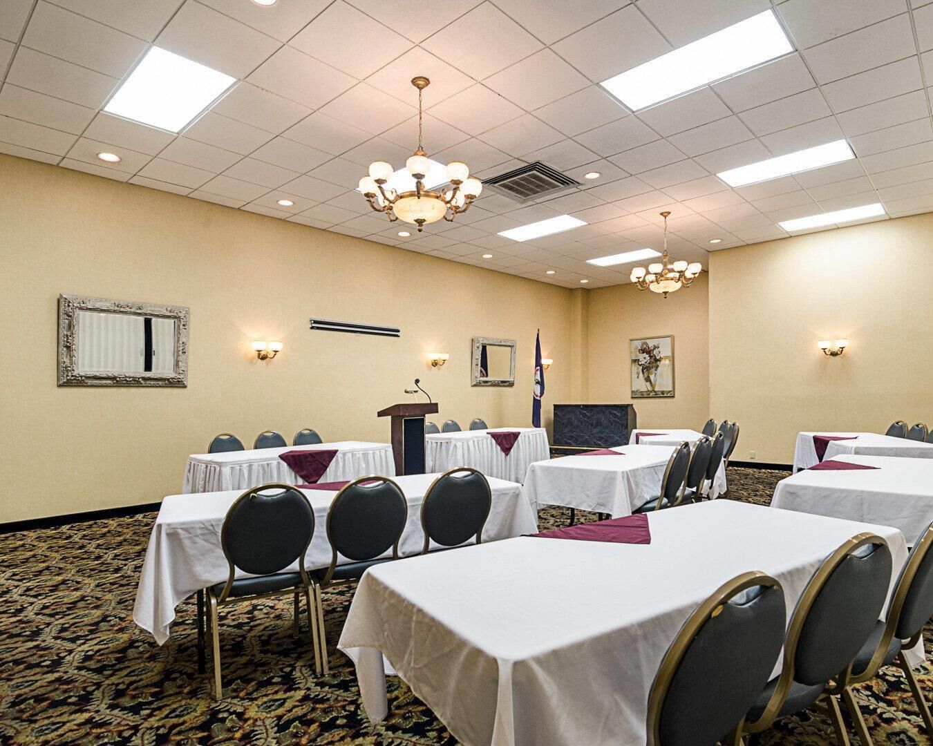 A conference room with tables, chairs, a podium, and a flag.