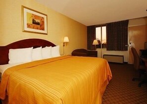 Una habitación de hotel con una cama grande, un escritorio, una silla y una ventana con cortinas.