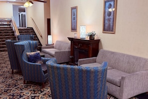 A living room with patterned armchairs, a sofa, a fireplace, and framed artwork on the walls. - Quality Inn Shenandoah Valley (New Market)