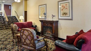 A hotel lobby with a fireplace, a staircase, and a carpeted floor. - Quality Inn Shenandoah Valley (New Market)