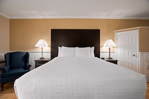 Relax in comfort with a large bed, two nightstands, and a cozy armchair.