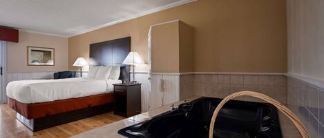 A hotel room with a bed, bedside lamps, a telephone, a bathtub, and a painting on the wall.