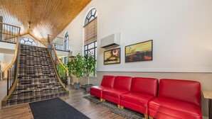 Un interior moderno con una escalera, un sofá de cuero rojo y obras de arte en las paredes.