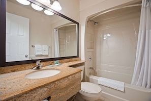 Enjoy a clean and functional bathroom with a granite countertop sink, large mirror, and bathtub with showerhead.