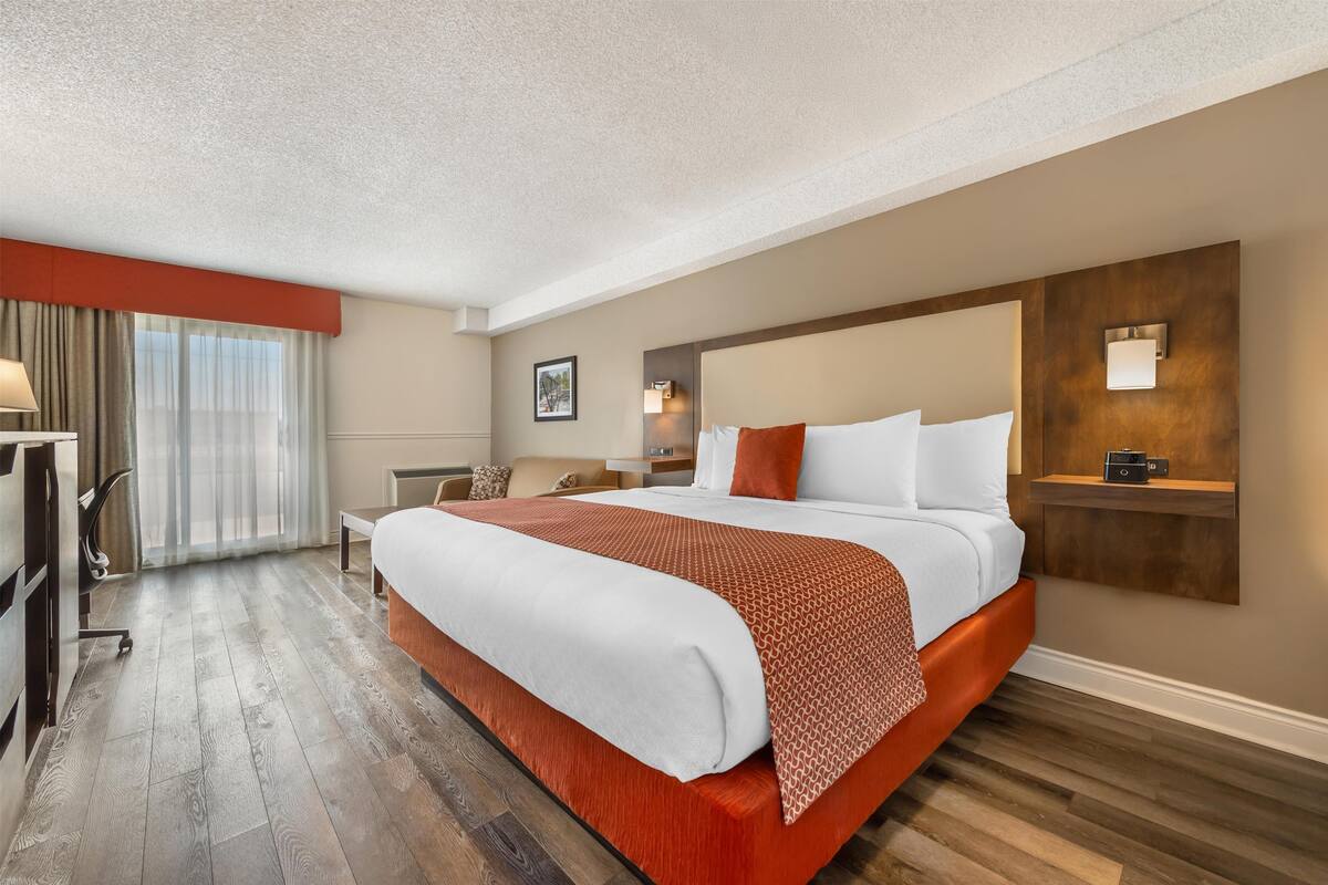 Een hotelkamer met een groot bed, een bureau en een stoel.