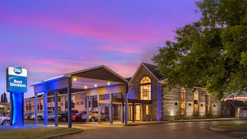 A Best Western hotel with a covered parking area and a stone building with arched windows.