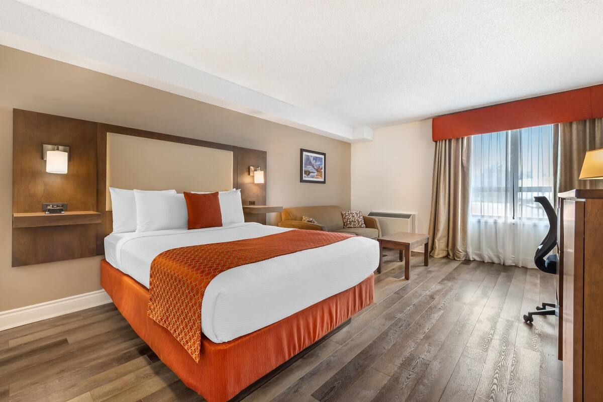 Een hotelkamer met een groot bed, een bureau, een stoel en een bank.