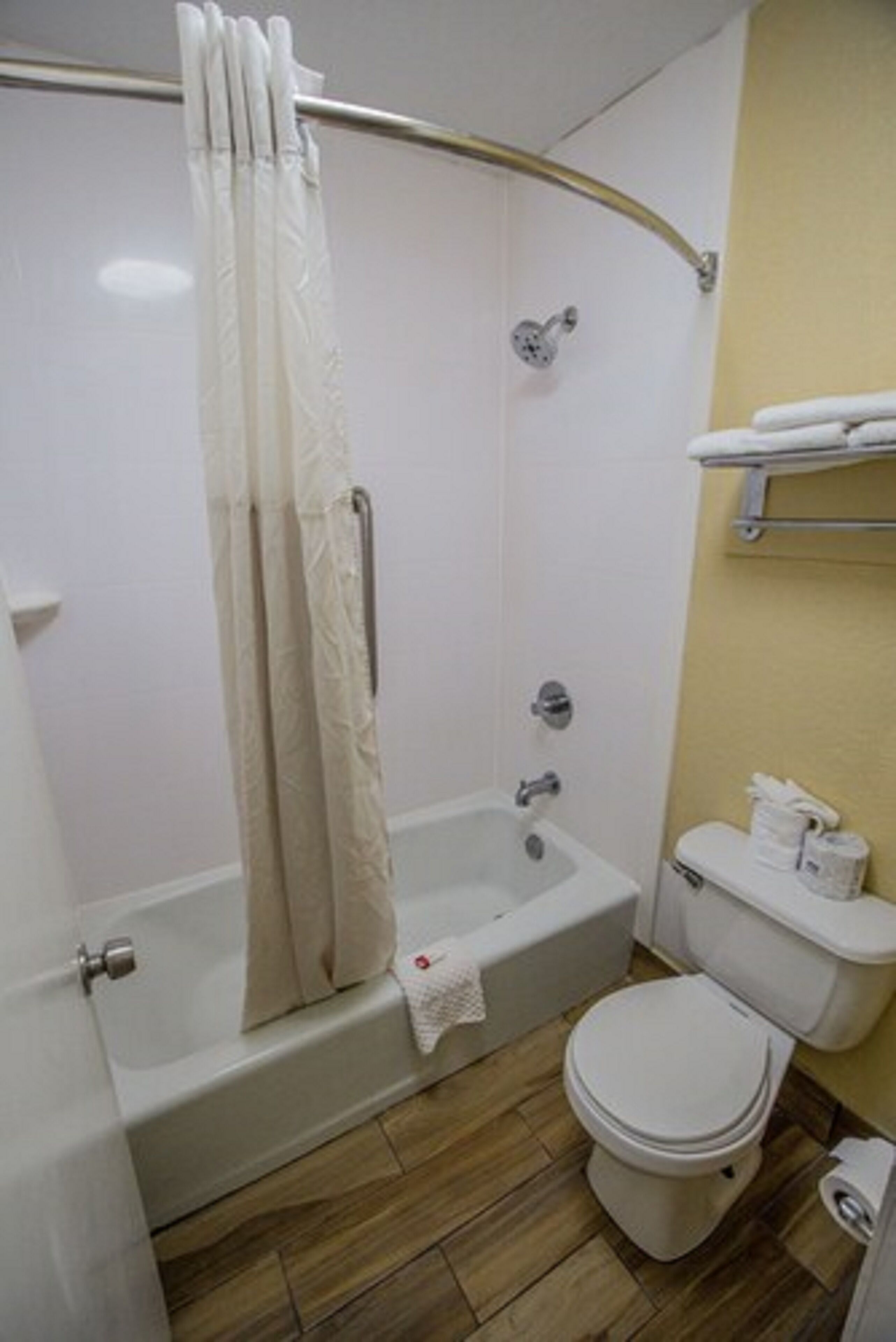 A bathroom with a bathtub, toilet, and shower curtain.