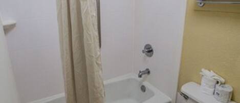 A bathroom with a bathtub, toilet, and shower curtain.