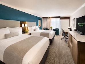 A hotel room with two beds, a desk, a chair, a television, and a window with curtains. - Wyndham Garden Oklahoma City Conference Ctr/Airpt/Bricktown (Oklahoma City)