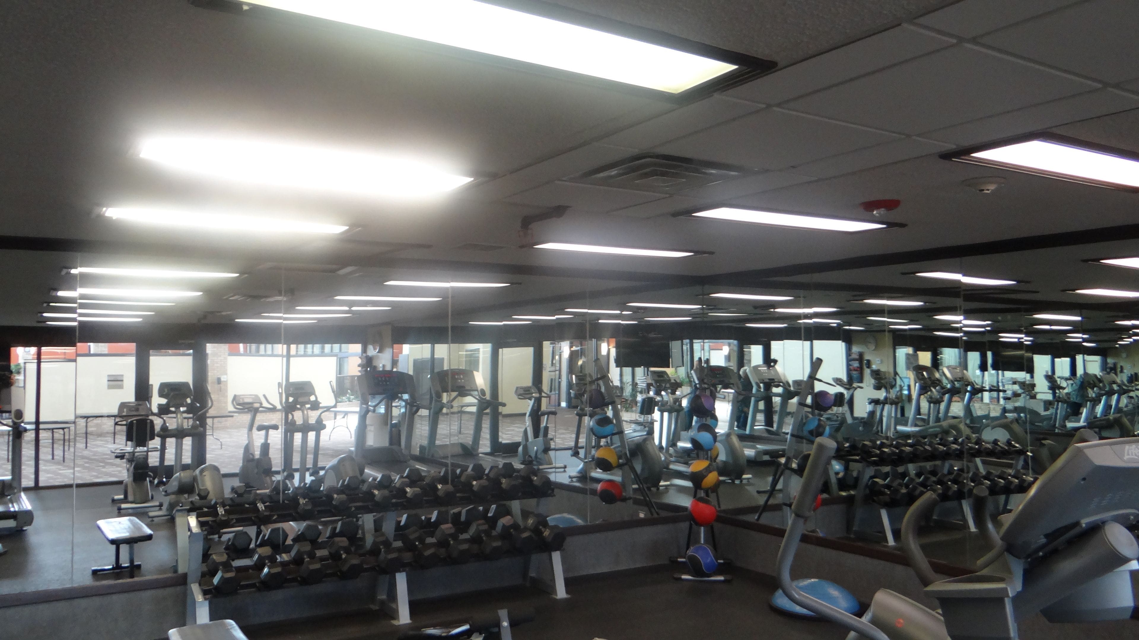 Un gimnasio con varios equipos de ejercicio, incluyendo cintas de correr, elípticas y jaulas de pesas.
