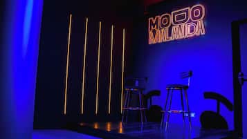 Una zona de bar con taburetes y un letrero de neón que dice "MODO LAVIDA".