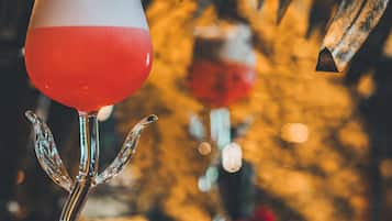 Um copo de cocktail com um design exclusivo, sobre uma mesa com uma rosa vermelha ao lado.
