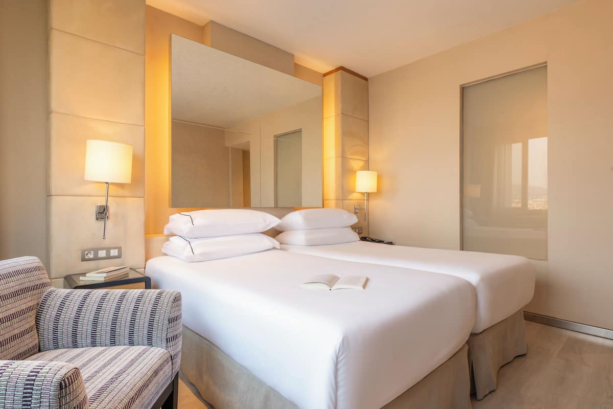 A hotel room with a large bed, two bedside lamps, a chair, and a mirror.