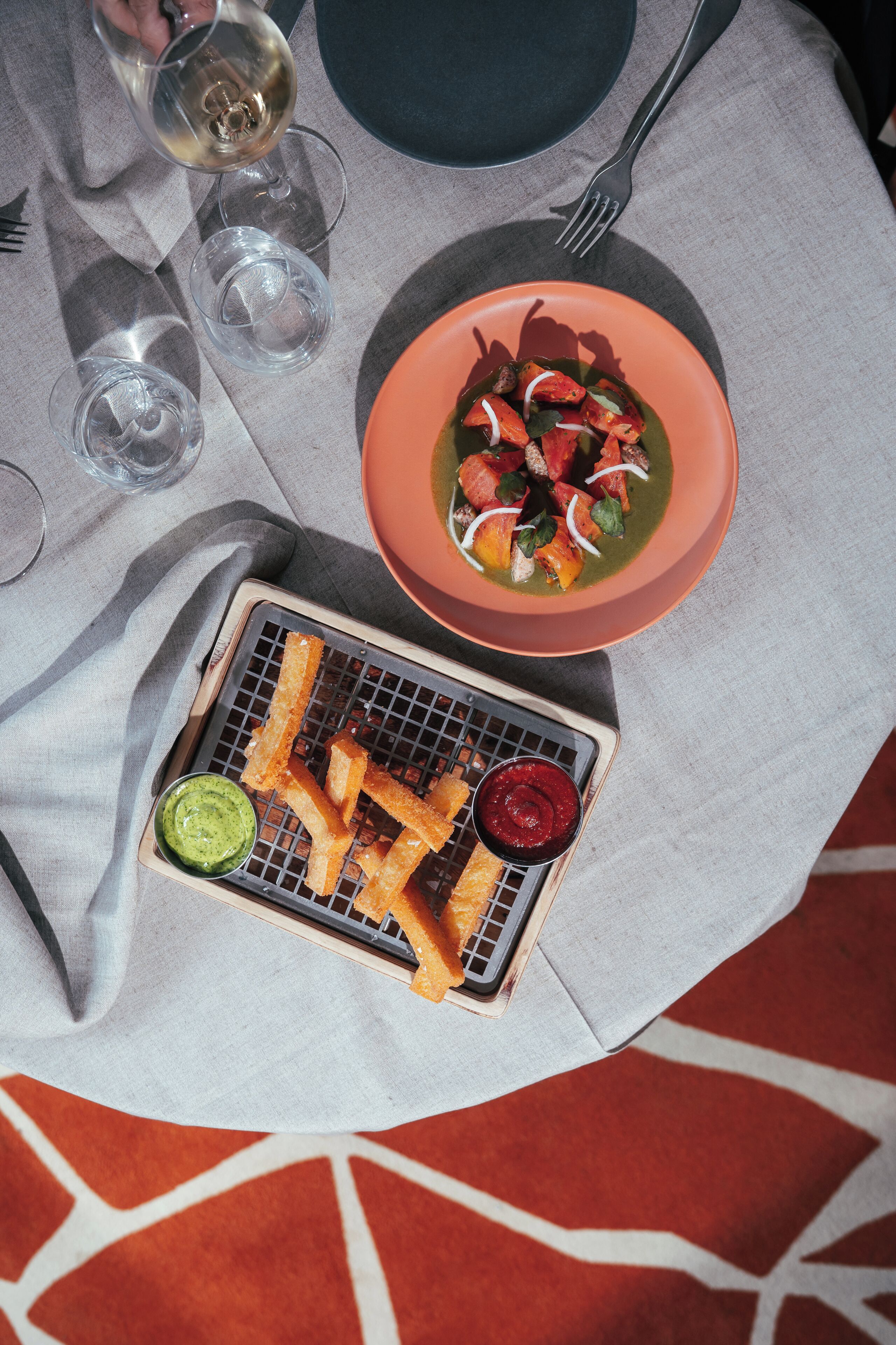 A table set with a bowl of soup, a plate of fries, and a glass of wine.