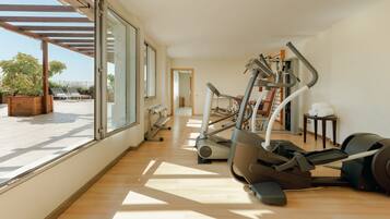 A spacious indoor gym with exercise equipment, large windows, and a view of the outdoors.