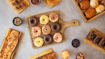 Diversas opciones de panadería, incluyendo rosquillas, galletas y una pizza sobre tablas de madera.