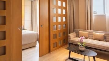 Une chambre d’hôtel avec un lit, un canapé, une table basse avec une plante et une cloison en bois.