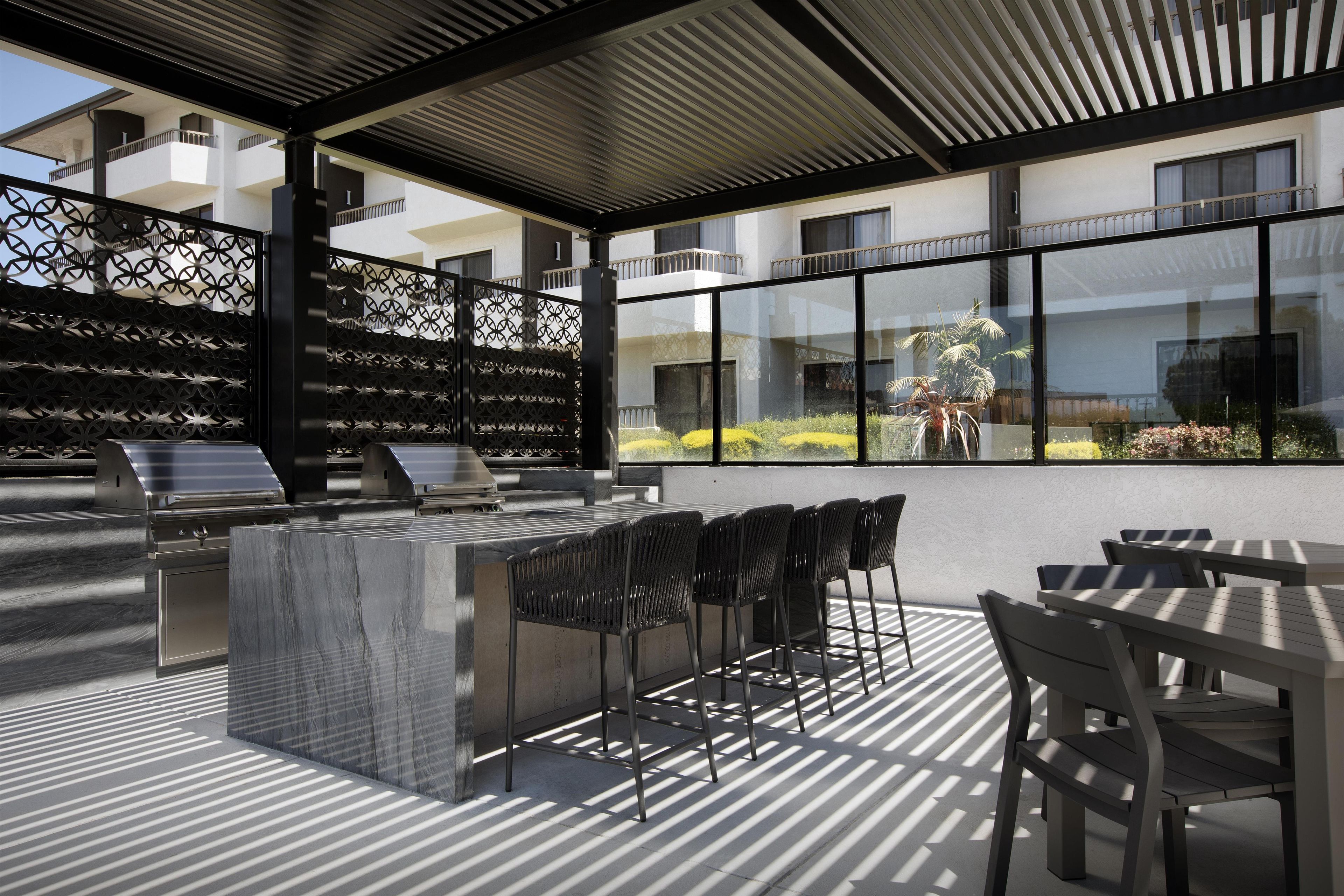 An outdoor patio area with a grill, seating, and a view of the building's exterior.