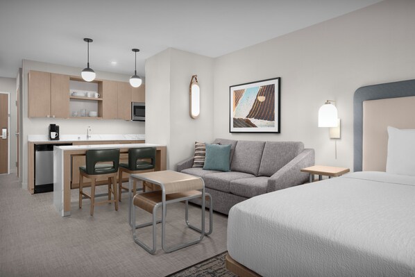 A modern hotel room with a kitchenette, a sofa, a bed, and a dining area. - Homewood Suites by Hilton Santa Maria (Santa Maria)
