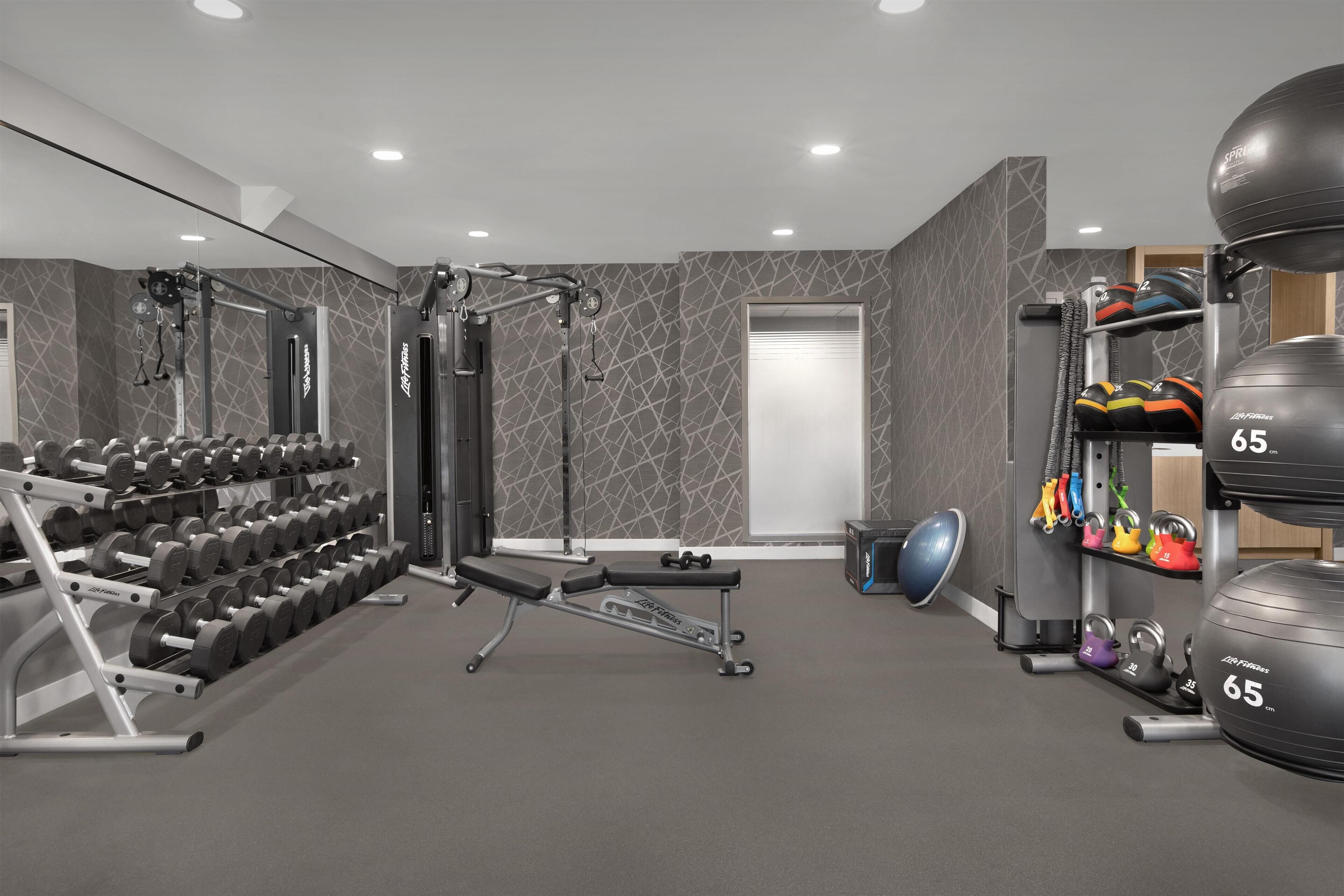 Uma academia com equipamentos de musculação, halteres e bolas de exercício.