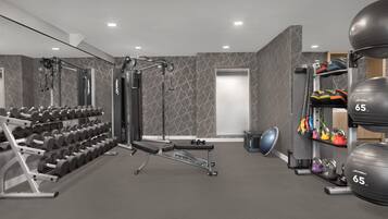 Uma academia com equipamentos de musculação, halteres e bolas de exercício.