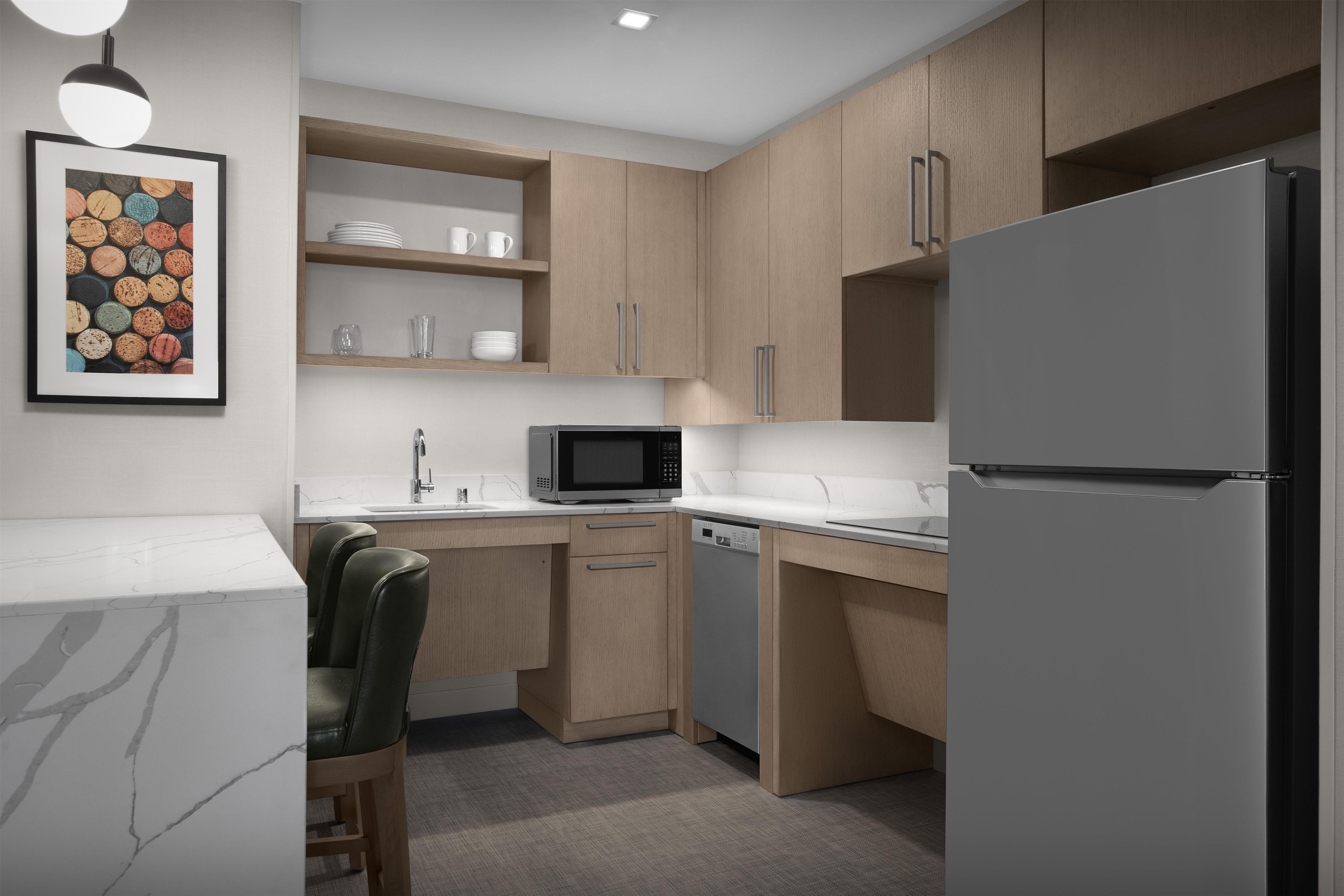Una cucina moderna con frigorifero, forno a microonde e zona pranzo con una sedia.